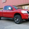 Red Nissan Titan with 2 inch front spacers and 1 inch rear blocks installed